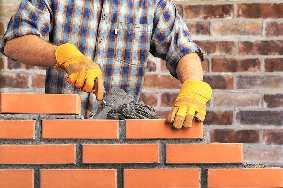 Bricklayer worker installing brick masonry