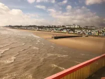 Bridge overlooking the sea shore and beach, village in distance background.