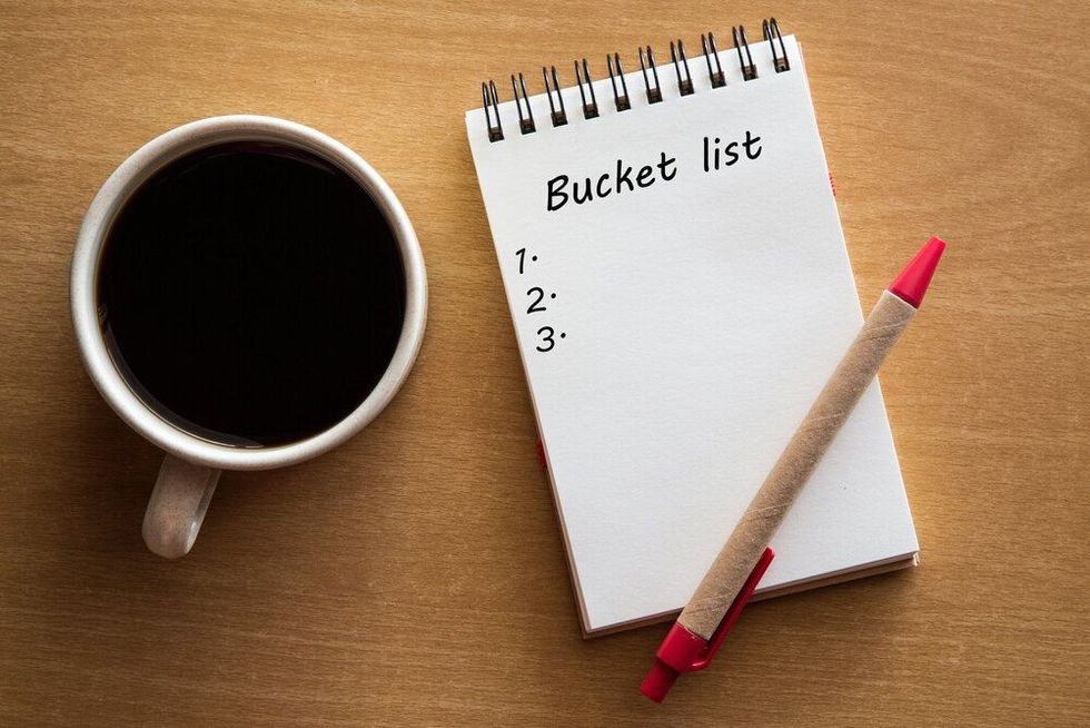Bucket list on notebook with a pen and cup of coffee