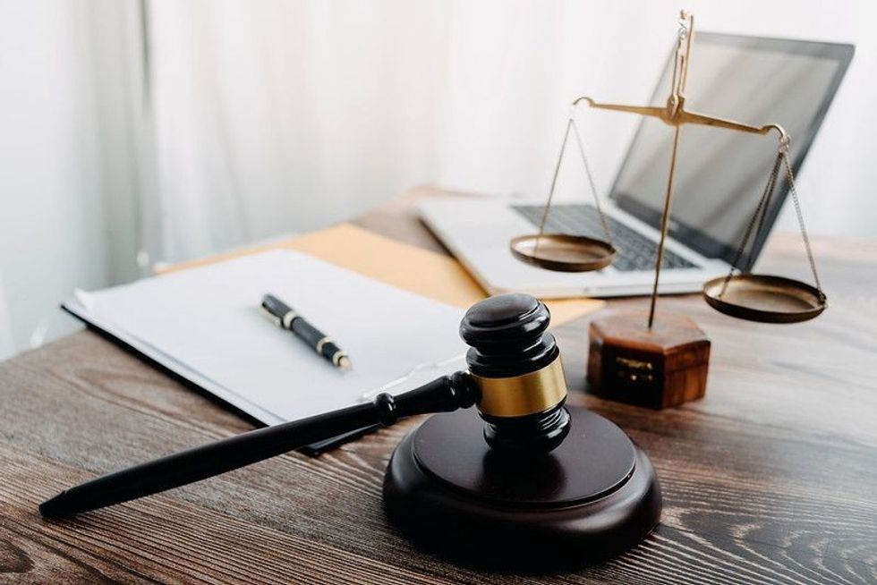 Business and lawyers discussing contract papers with brass scale on desk in office