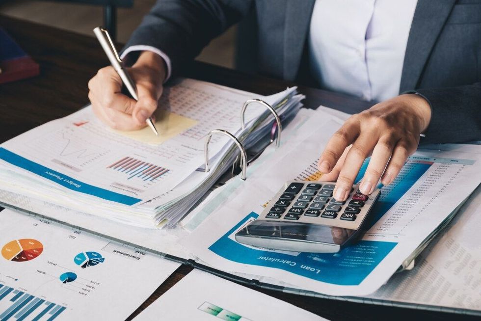 Business woman using calculator and laptop for do math finance on wooden desk in office