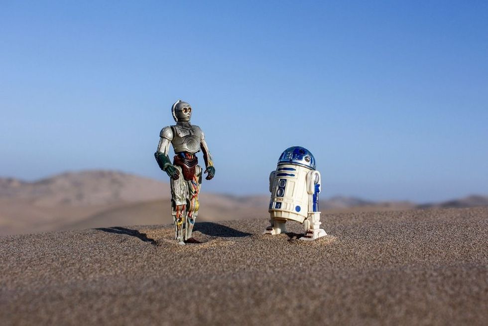 C3PO and R2D2 Hasbro action figures from Star Wars standing on sand