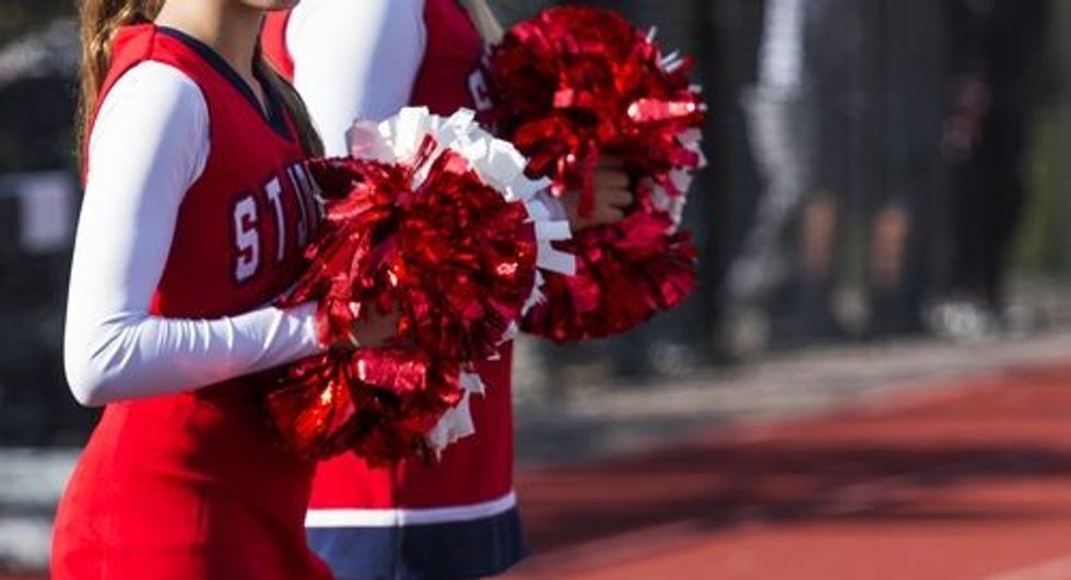 Cheerleaders pom poms glistening in the sun during a high school football game.