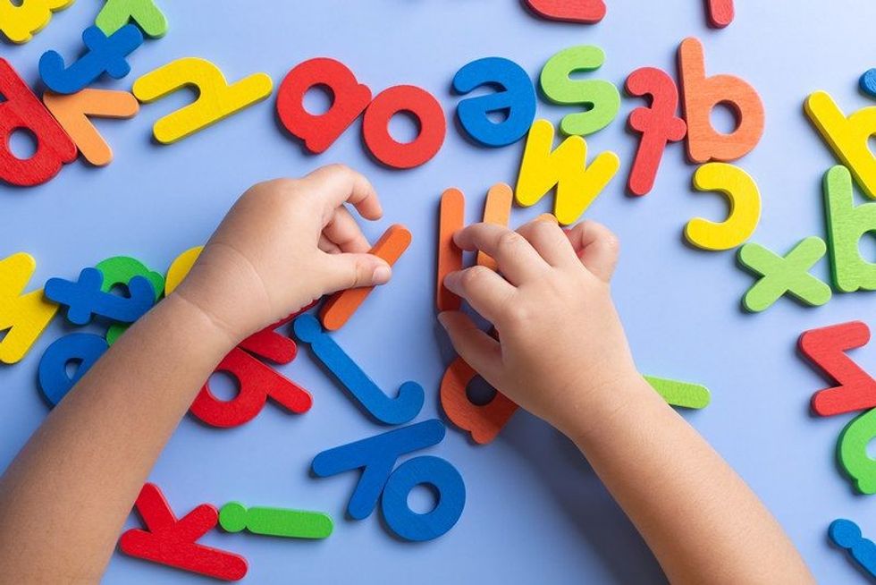 Child arm learning alphabet with wooden toys