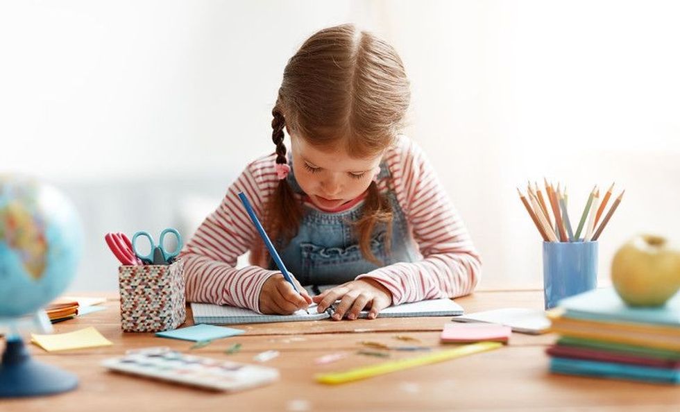 Child girl doing homework writing and reading at home.
