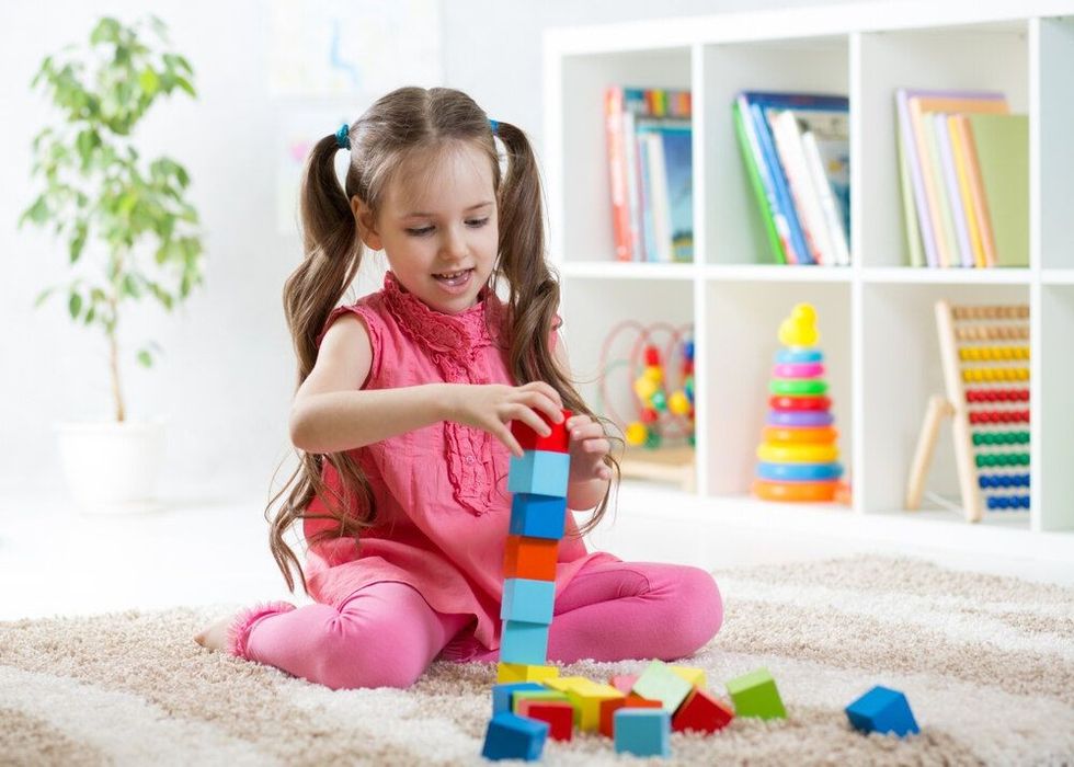 child little girl playing wooden toys at home or kindergarten