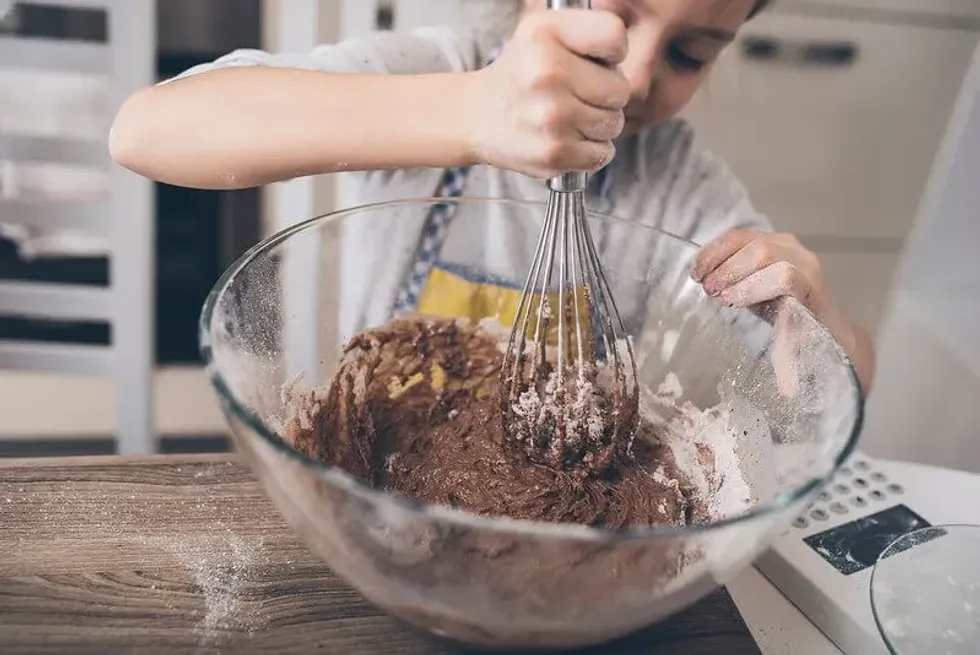 Child mixing chocolate cake batter for his hedgehog cake.