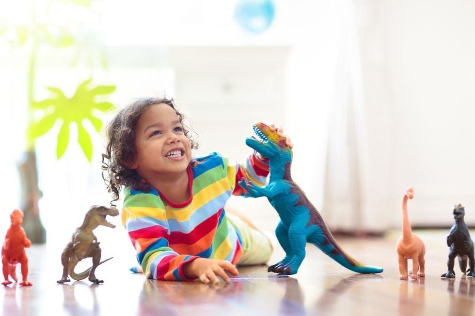 Child playing with colorful toy dinosaurs.