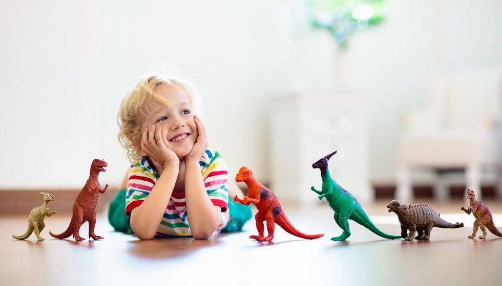 Child playing with colorful toy dinosaurs.