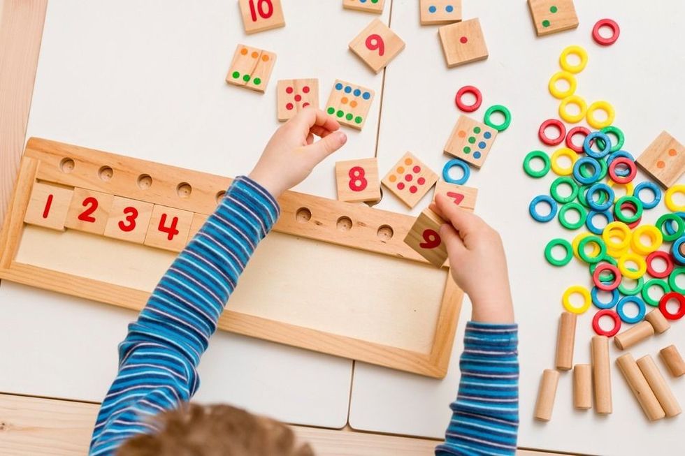 Child playing with different color wooden rings.
