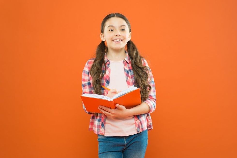 Child reading a book on orange background.