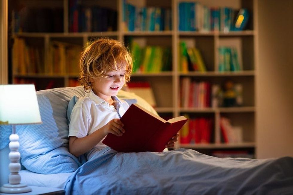Child reading book in bed.