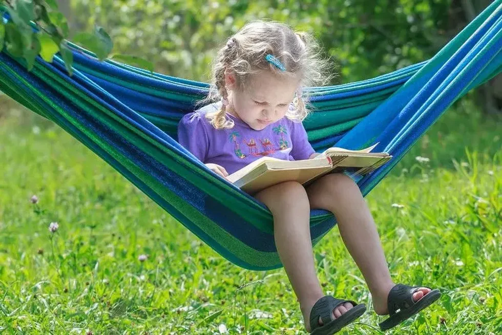 Child reading outside in a hammock