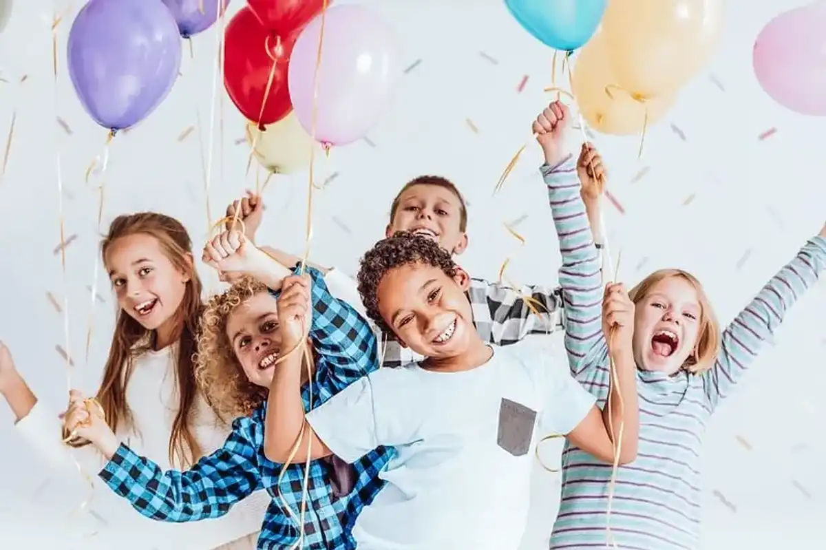 Children at a birthday party smiling happily at funny party jokes