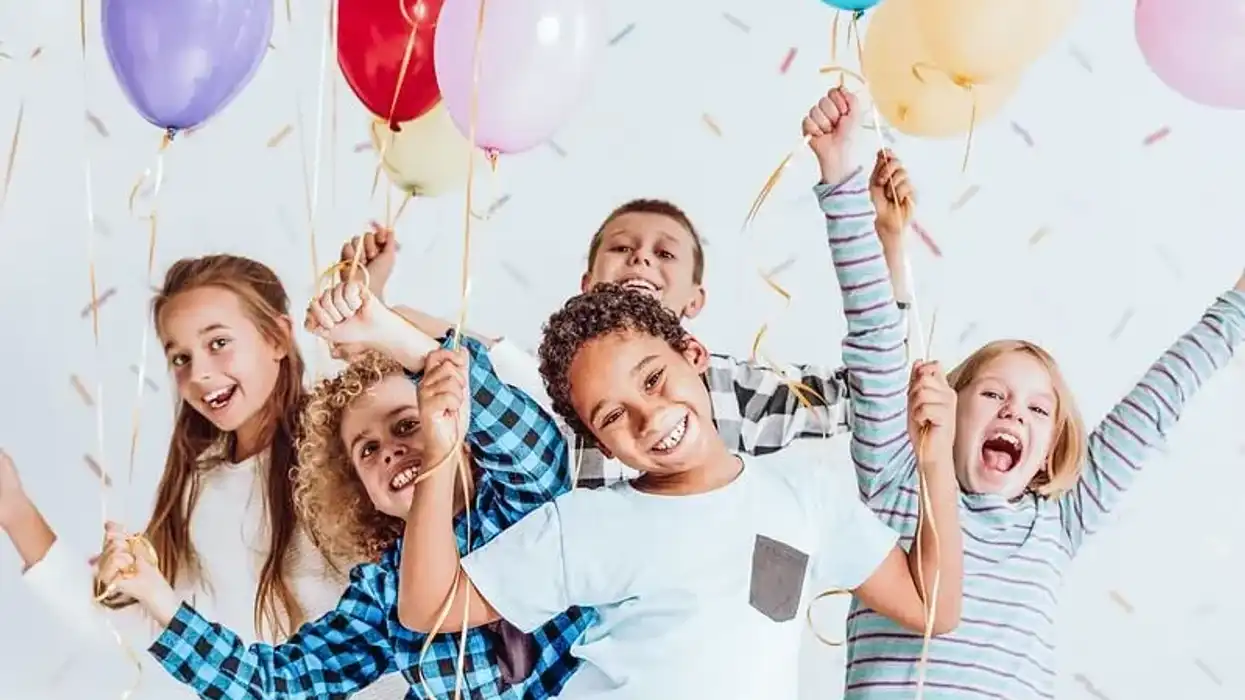 Children at a birthday party smiling happily at funny party jokes