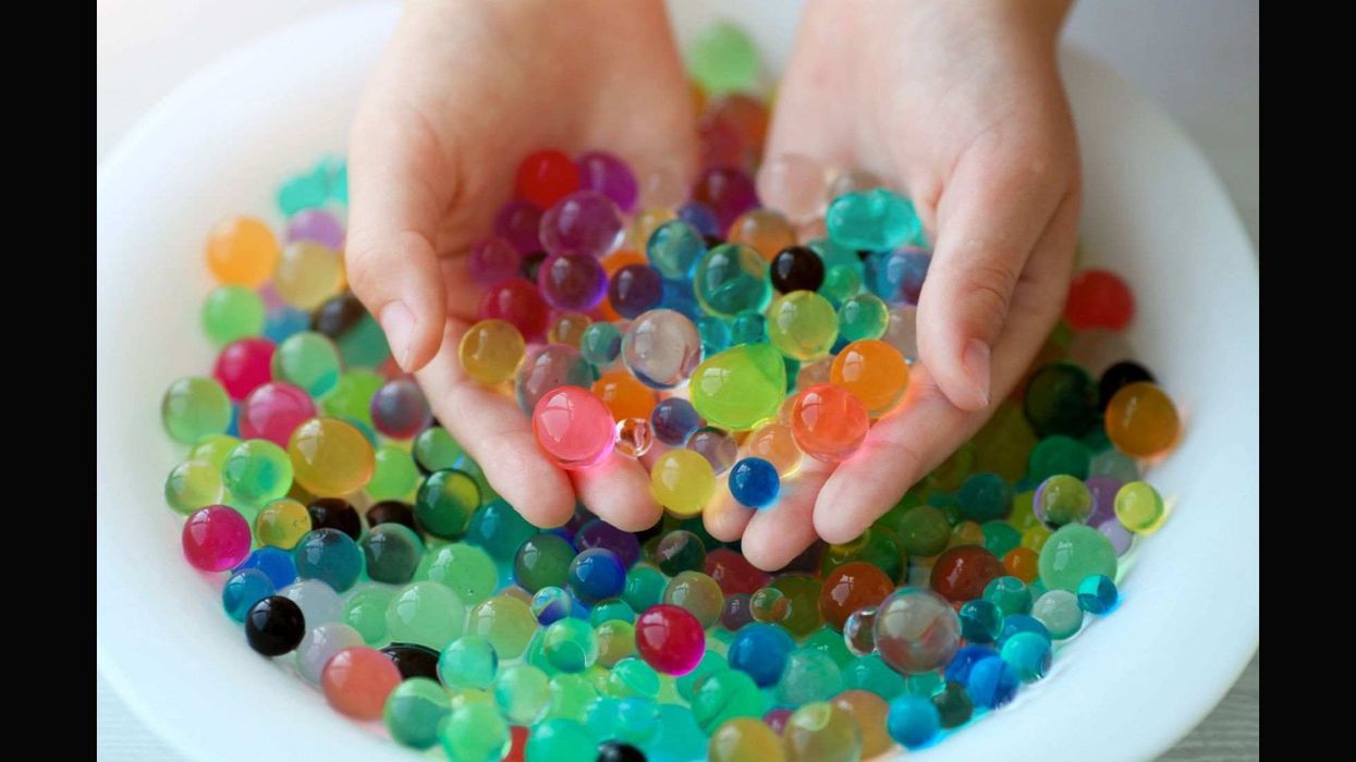 Children is hands play orbeez in a plate.