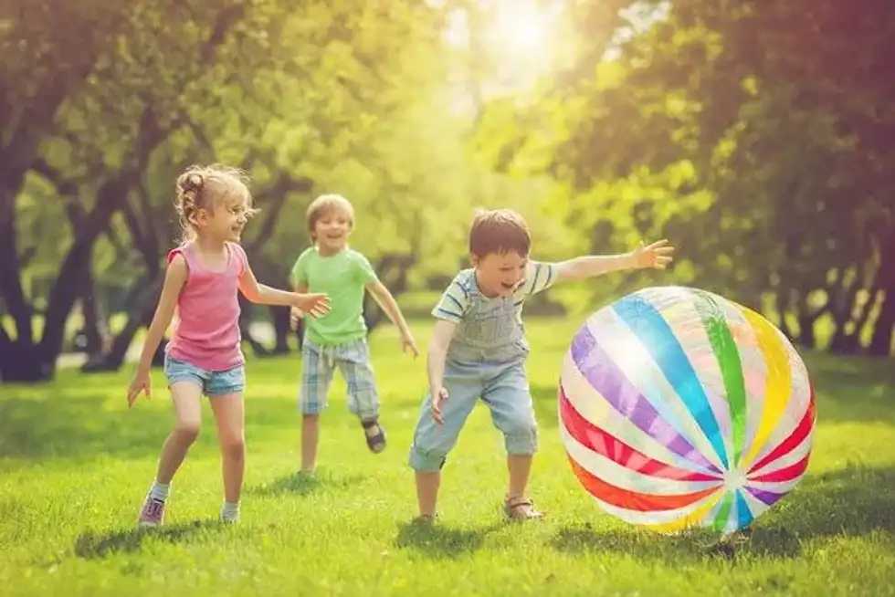 Children playing with a giant inflatable ball outside.