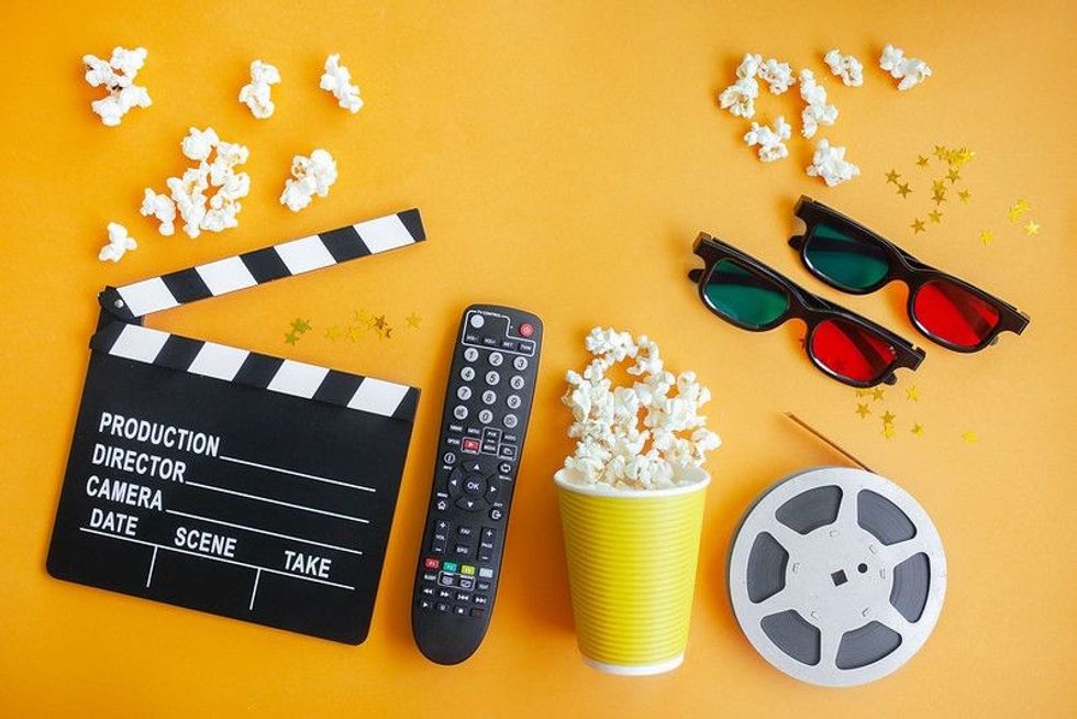 Clapboard, popcorn, remote  and movie reel on yellow background