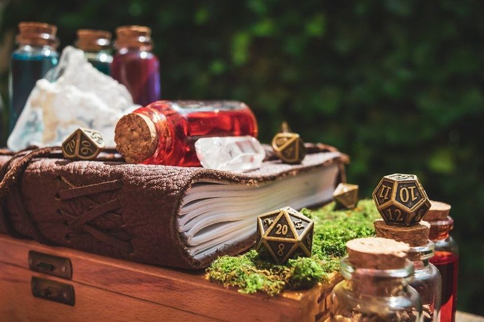Close-up of a 20-sided metallic role-playing gaming die next to a leather-bound book