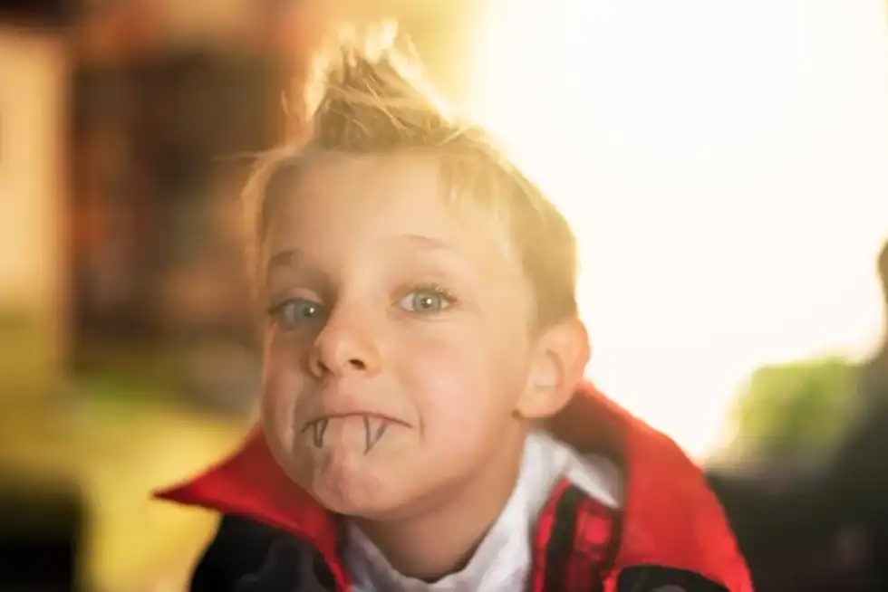Close up of a young boy dressed up as a vampire for Halloween with fangs drawn on for an effective costume.