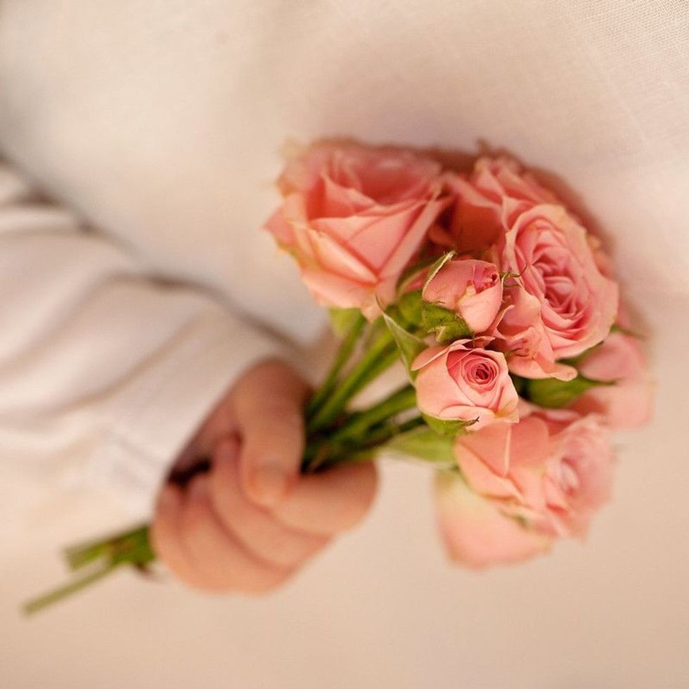 Close-up of newborn baby hand holding a bouquet of flowers.