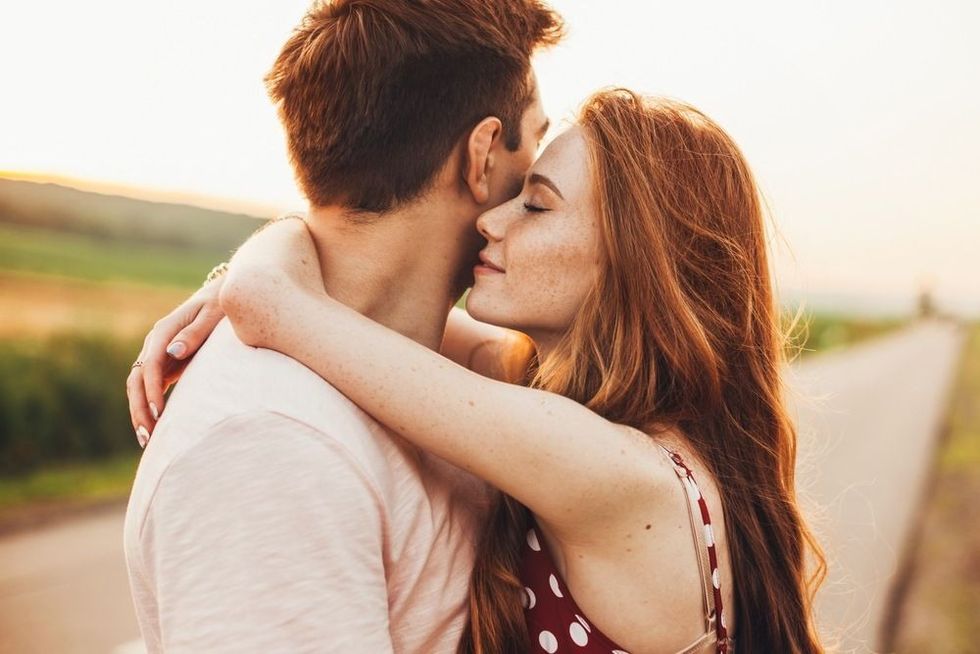 Close-up portrait of a caucasian young loving couple embracing while standing on a roadside.