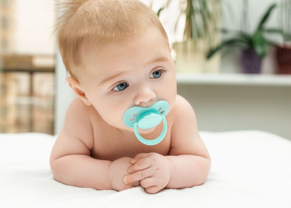 Close-up portrait of a little baby boy with pacifier on mouth.