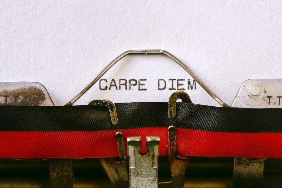 Closeup of an old typewriter and the text carpe diem typewritten with it in a foil