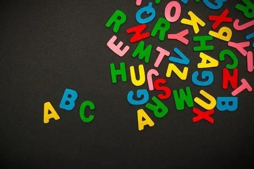Colorful alphabets scattered on black background