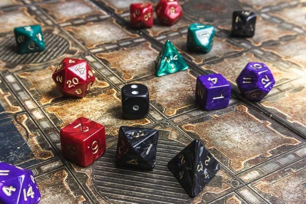 Colorful tiefling dices on ground.
