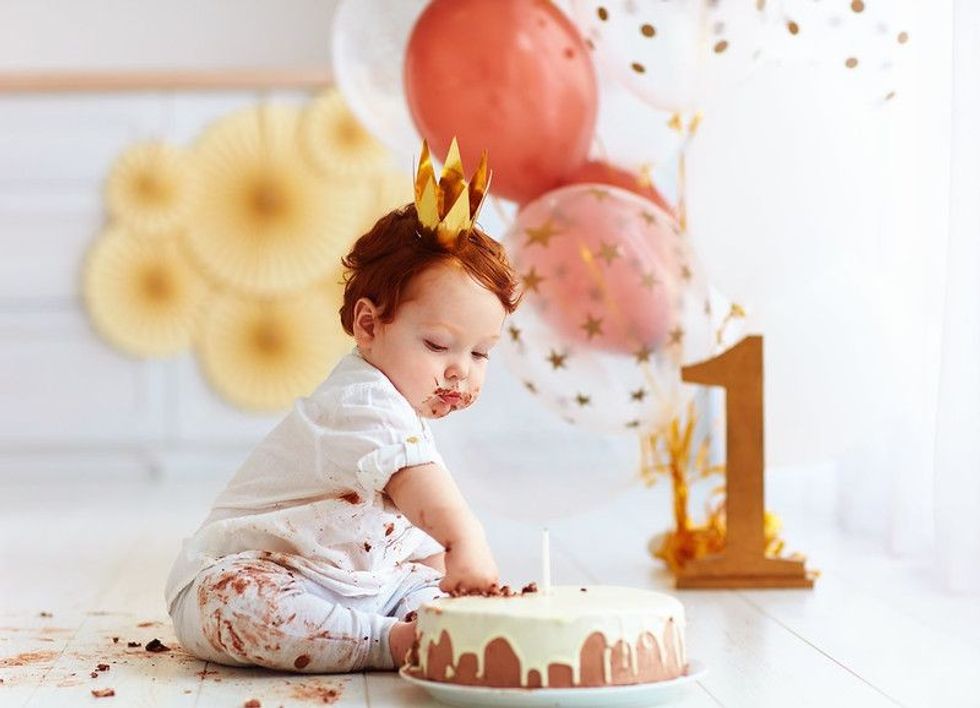 Curious baby boy poking his finger in his birthday cake