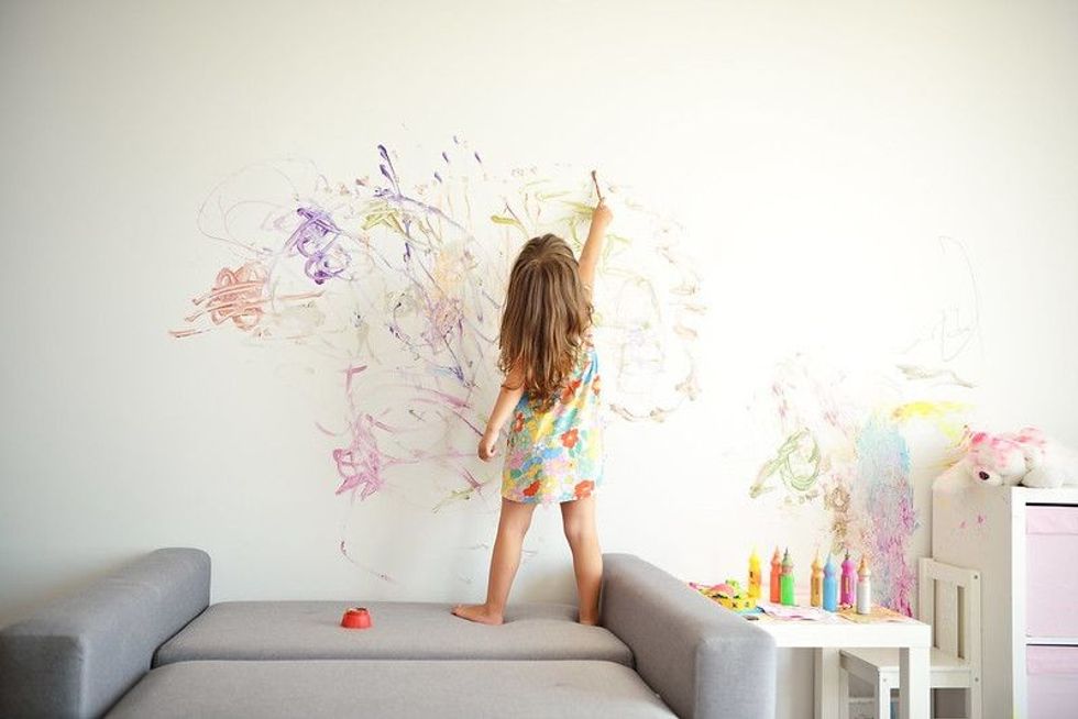 Curly cute little toddler girl painting.