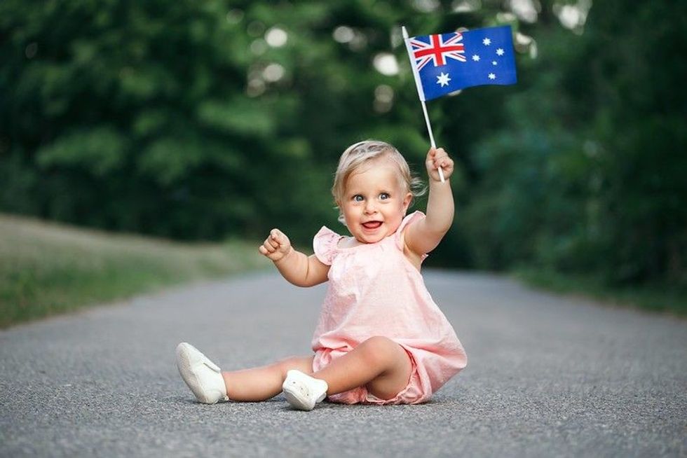 Cute adorable Caucasian baby girl waving Australian flag.