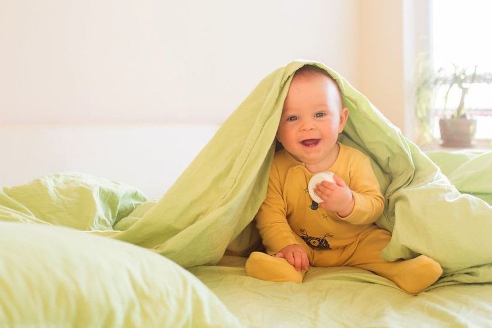 Cute baby boy under green blanket.