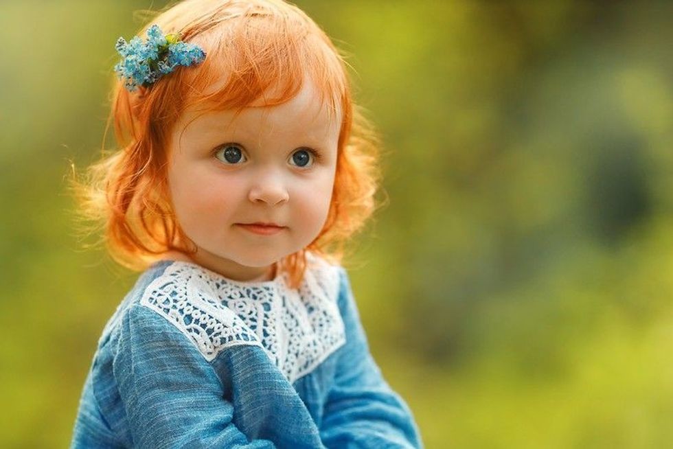 Cute baby girl with red hair in blue dress