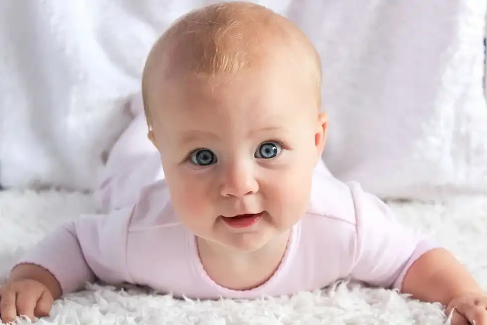 cute baby lying on a white fur beddings looking into the camera with beautiful grey eyes