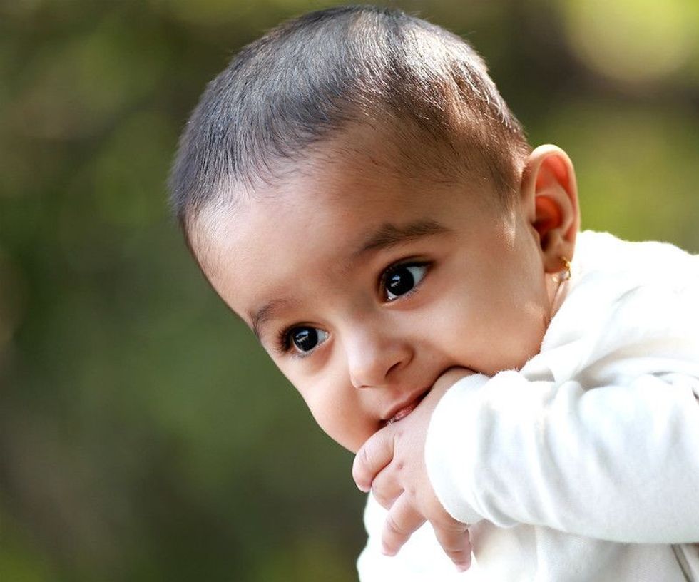 Cute Indian newborn baby sucking on their thumb