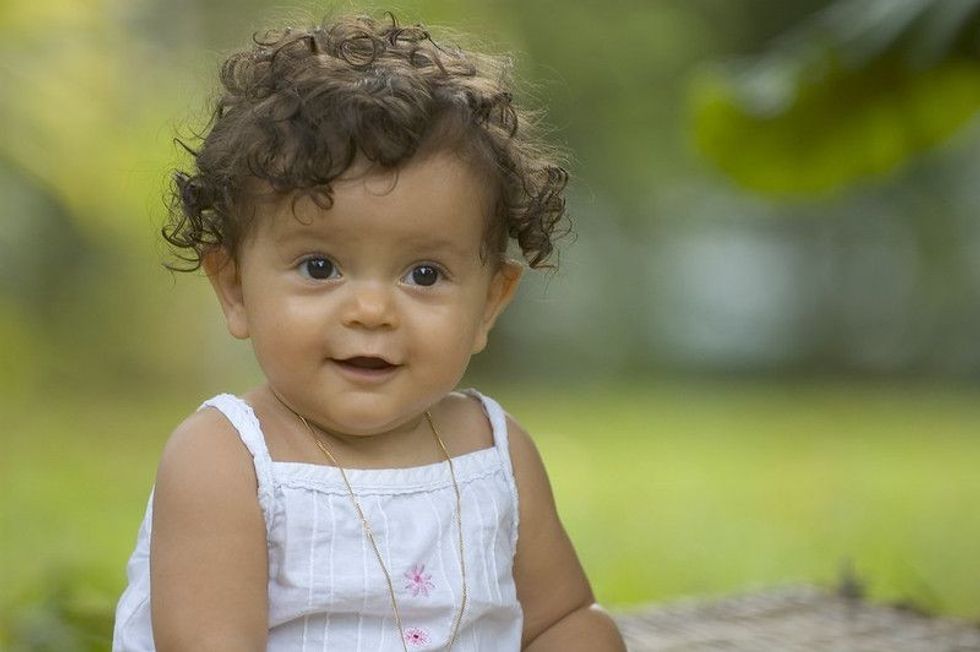 Cute little baby girl sitting in a garden.