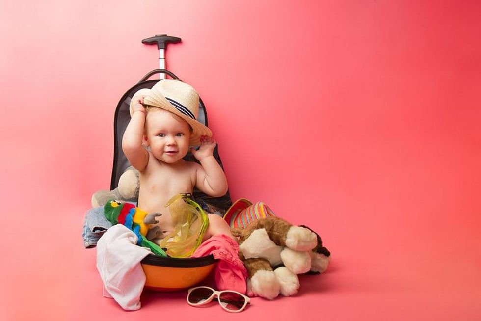 Cute little baby sitting in a travel suitcase.