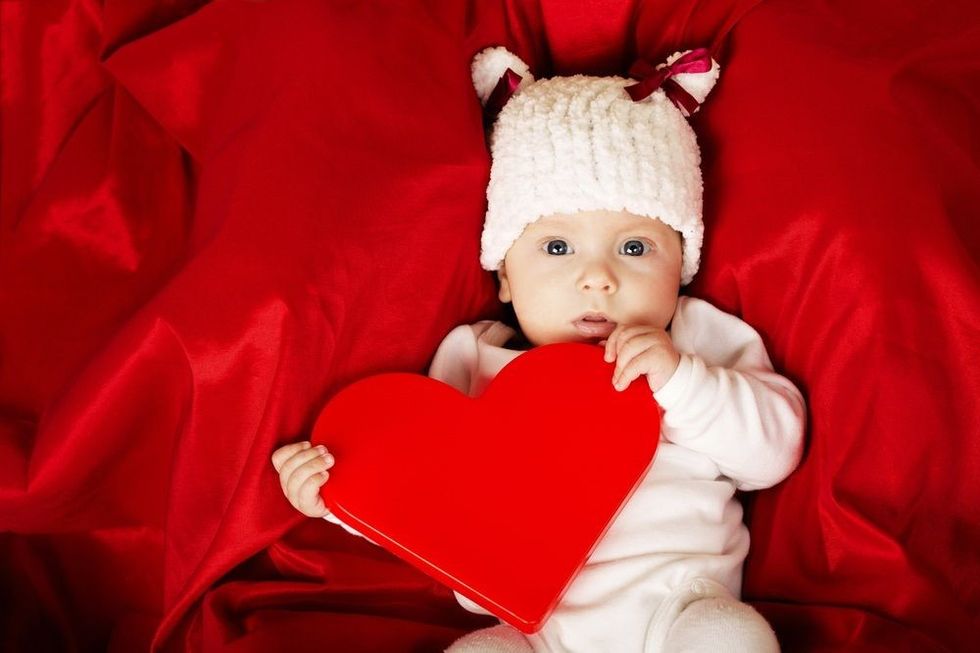 Cute little baby with heart in hands
