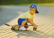 Cute little boy playing with skateboard outdoor