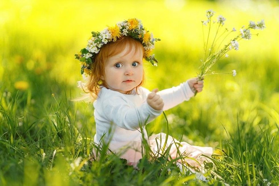 Cute little girl is wearing beautiful spring wreath outdoors.