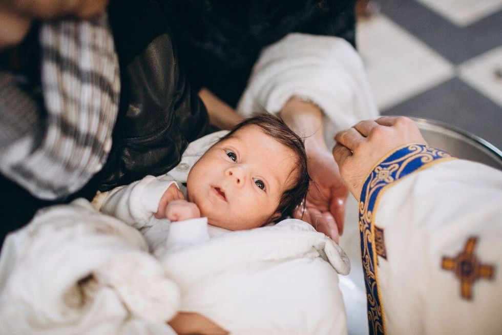 Cute little head of a girl under holy water at christening ceremony with priest