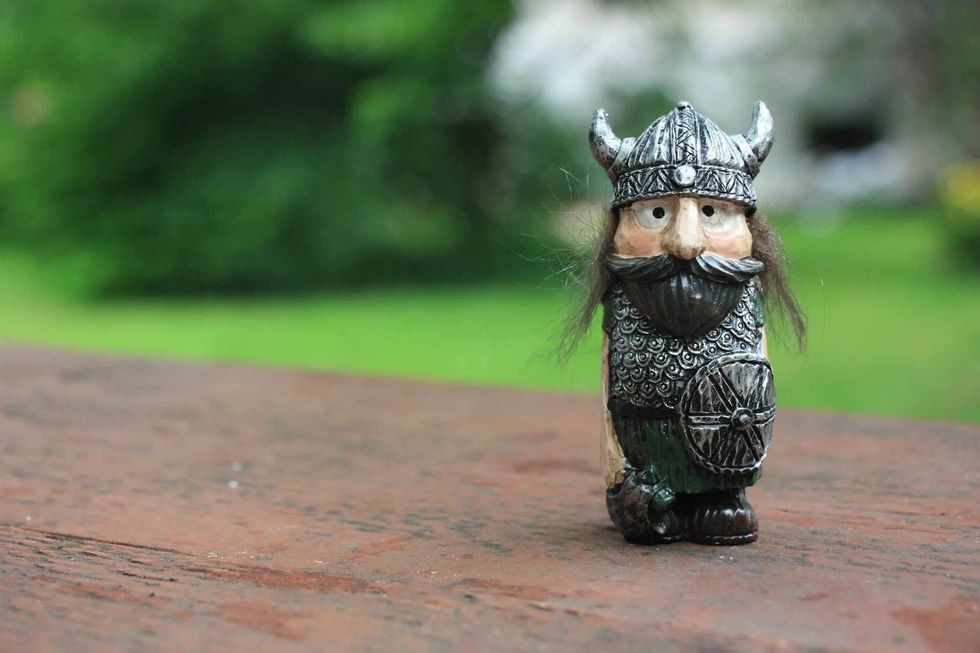 Cute little viking soldier figurine standing on wooden platform