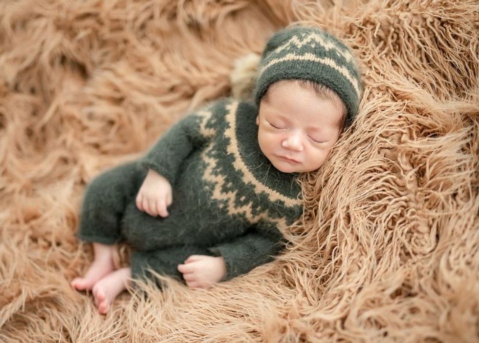 Cute sleeping newborn baby on brown fur wearing knitted clothes