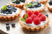Different berry tarts pastries on table