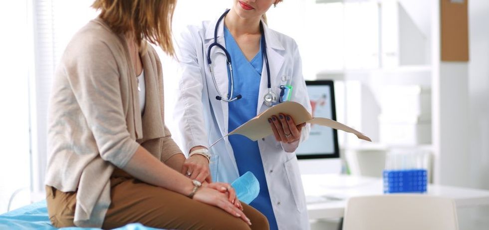 Doctor and patient discussing something while sitting at the table .