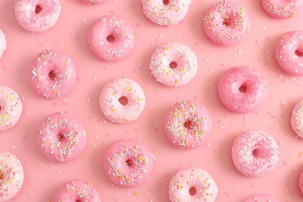 Donuts with sprinkles on pink background.