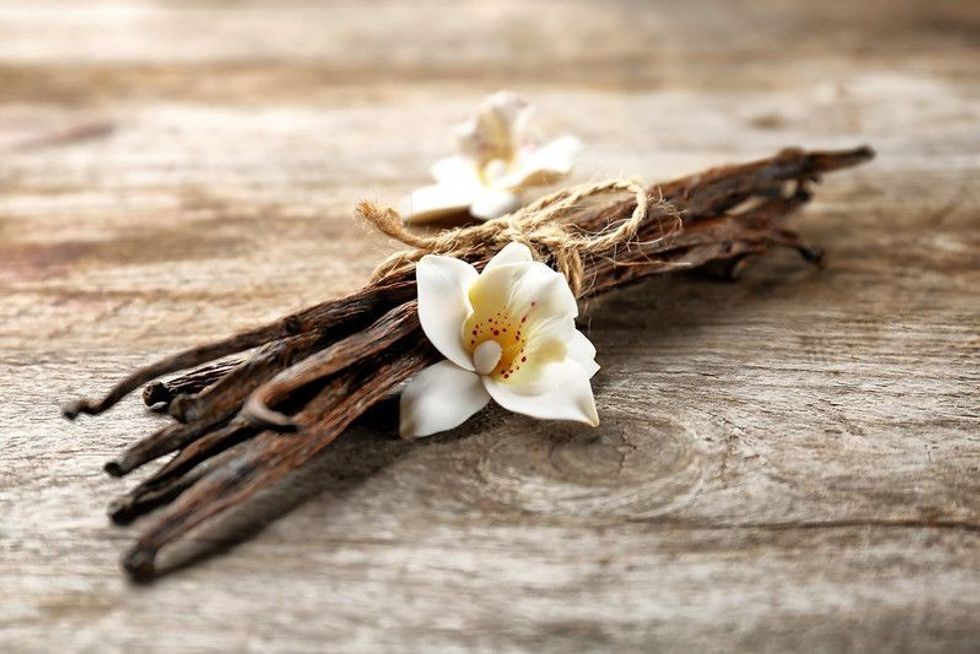 Dried vanilla pods and flower on wooden background.