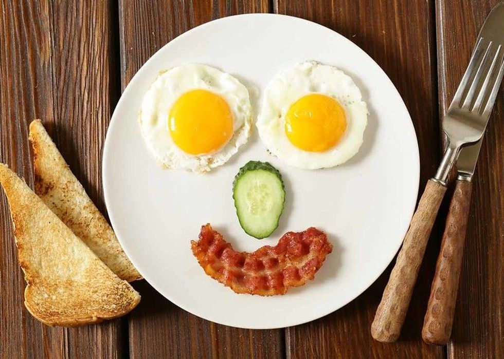Eggs and bacon kept in the shape of face on a plate